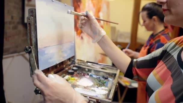 Women artists are drawing on canvas with a brush. Drawing landscape on canvas. — Stockvideo