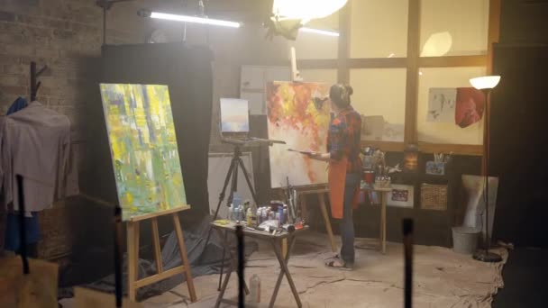 Femme artiste dessine sur toile avec peinture à l'huile. . Loft d'art. Vidéo De Stock