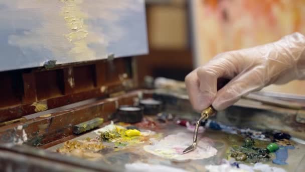 Mujer artista está dibujando sobre lienzo con un cuchillo de paleta y pintura al óleo. Dibujo paisaje sobre lienzo. — Vídeo de stock