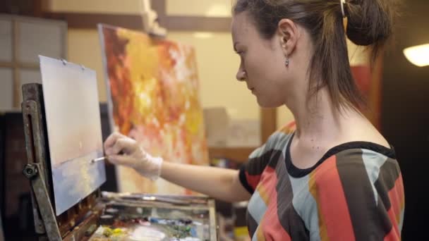 Γυναίκα καλλιτέχνης ζωγραφίζει σε καμβά με ένα μαχαίρι παλέτα και ελαιογραφία. Σχέδιο τοπίου σε καμβά. — Αρχείο Βίντεο