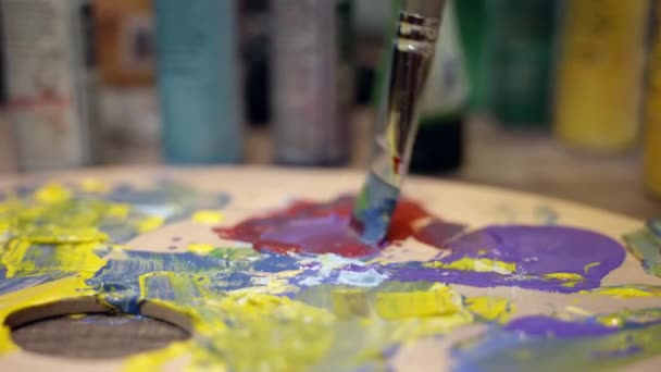 Vrouw kunstenaar is het mengen van olieverf met een borstel op een schilderij palet. — Stockvideo