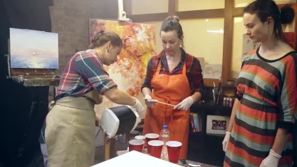 Umělkyně nalívají bílou barvu do sklenic. Umělecká spolupráce na workshopu. — Stock video