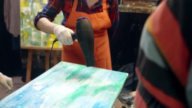 Kadın sanatçılar tuvale akrilik boya döküyorlar. Atölyede sanatsal işbirliği.