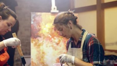 Kadın sanatçılar camlara akrilik boya karıştırıyor. Resim yapmaya hazırlanıyorum. Atölyede sanatsal işbirliği.