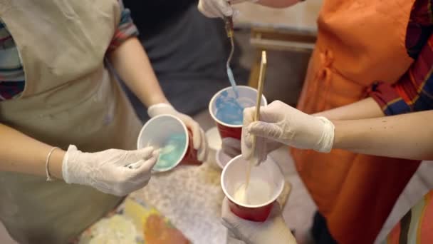 Umělkyně míchají akrylovou barvu v plastovém kelímku. Umělecká spolupráce na workshopu. — Stock video