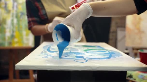 Las mujeres artistas están vertiendo pintura acrílica en el lienzo. Colaboración artística en taller. — Vídeo de stock