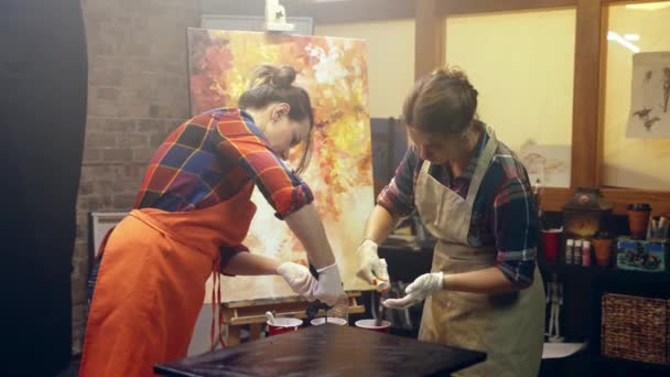 Femmes artistes verser de la peinture blanche dans des verres. Collaboration artistique en atelier. — Video