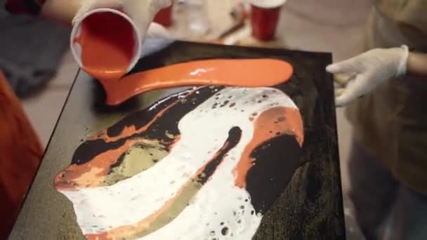 Las mujeres artistas están vertiendo pintura acrílica en el lienzo. Colaboración artística en taller. — Vídeo de stock