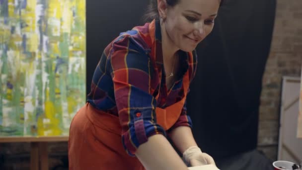 Mujeres artistas smering pegamento blanco en el lienzo. Colaboración artística en taller. — Vídeo de stock