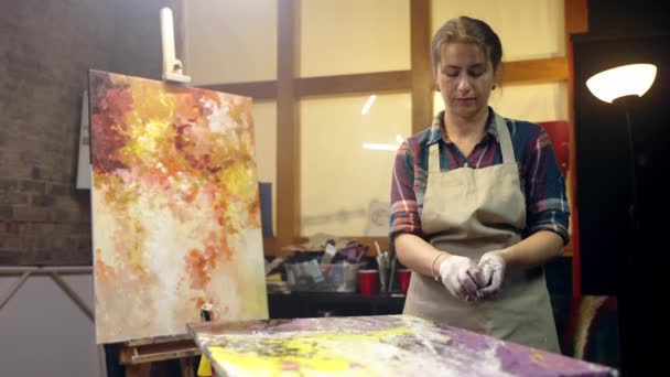 女性アーティストは、芸術的なワークショップの後、彼女の絵画の輝きを離陸しています。仕事は終わりだ. — ストック動画