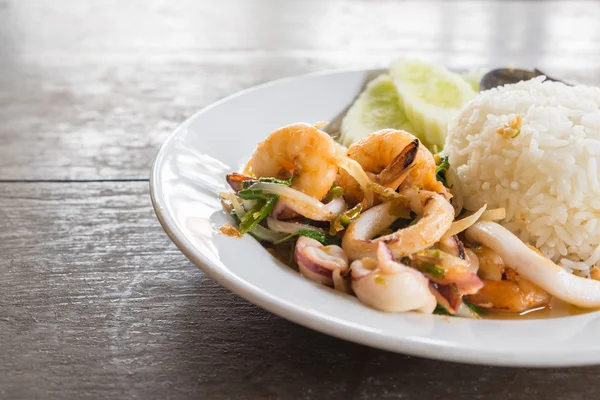 Arroz cubierto con mariscos fritos picantes y albahaca — Foto de Stock