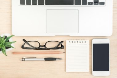 Dizüstü bilgisayar, kağıt, cep telefonu, kalem, kurşun kalem ve gözlük ahşap t