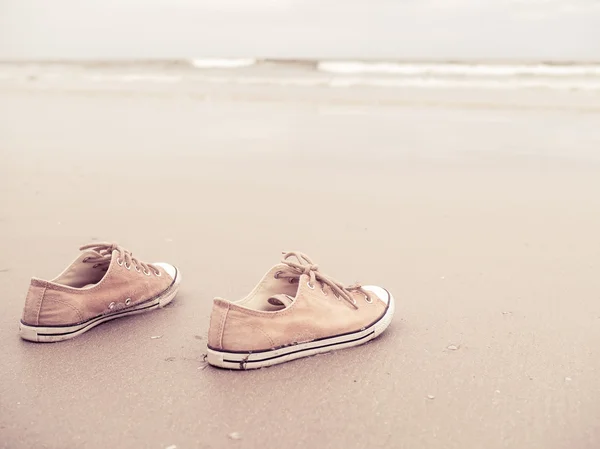 Yellow vintage canvas shoes on the sand beach