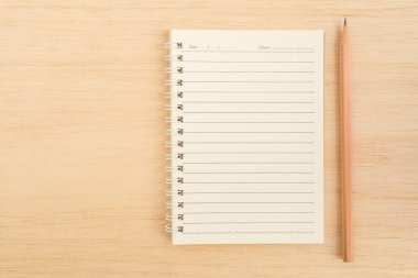 Üstten görünüm açık sarmal çizgi kağıt defter ve kahverengi kalem 