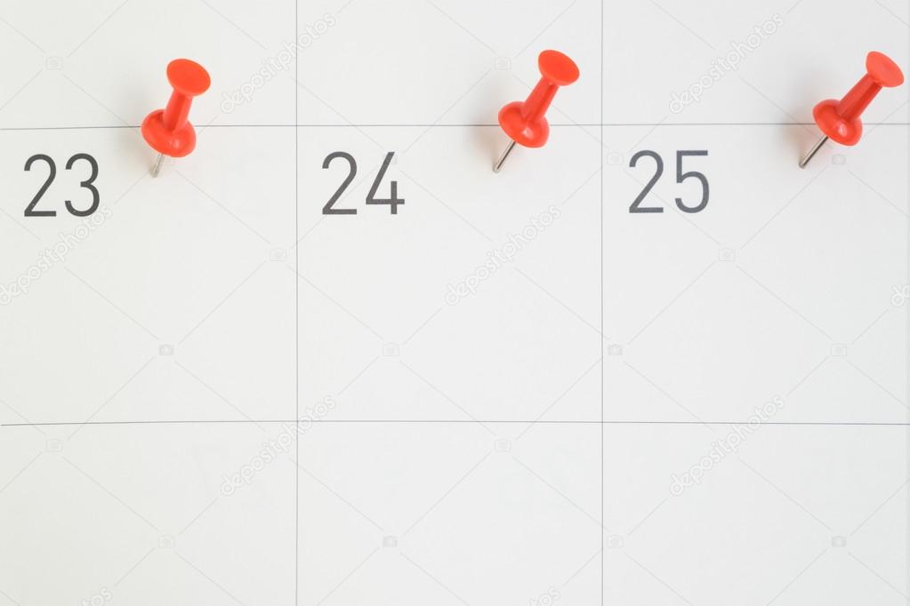 Red pins pinned on the dates of the month on calendar paper