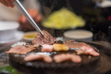 Asyalı kadınlar bir restoranda et veya domuz eti yemek için çubuk kullanırlar..