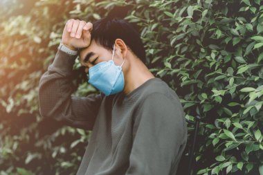 Adamın başı ağrıyor ve Coronavirus covid-19 'un yayılmasını önlemek için maske takıyor.