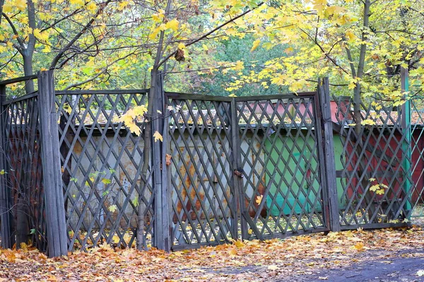 黄色の秋の葉に門のある木製の格子柵の後ろのガレージ — ストック写真
