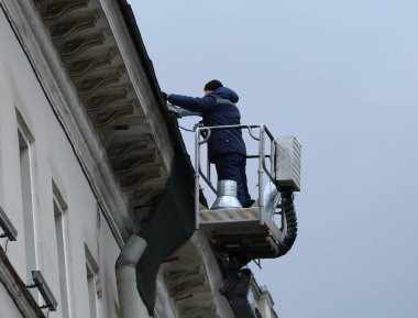 Mavi üniformalı bir işçi, endüstriyel bir asansörün çatısını tamir ediyor. Nevsky Prospekt, St. Petersburg, Rusya, Mart 2021