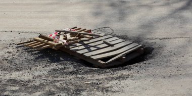  Asfalt yolda bir çukur ahşap paletlerle kaplıdır.