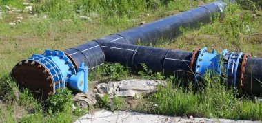 Yeşil çimenlikteki büyük siyah lağım borularına bağlanıyor