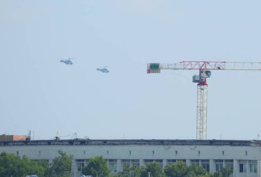 Gökyüzünde, Bolsheokhtinsky Prospekt, St. Petersburg, Rusya, Temmuz 2021 'de bir vincin yanında iki Rus donanma helikopteri var.