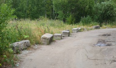Taşrada bir toprak yolun kenarında beton bloklar var.