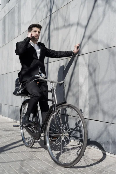 Бизнесмен останавливает велосипед, чтобы поговорить по телефону. — стоковое фото