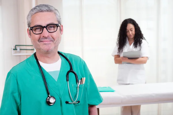 Arzt vor Kamera und Krankenschwester in der Klinik — Stockfoto