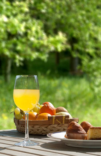 Mesa de desayuno con magdalenas de pastel y jugo de naranja en el campo — Foto de Stock