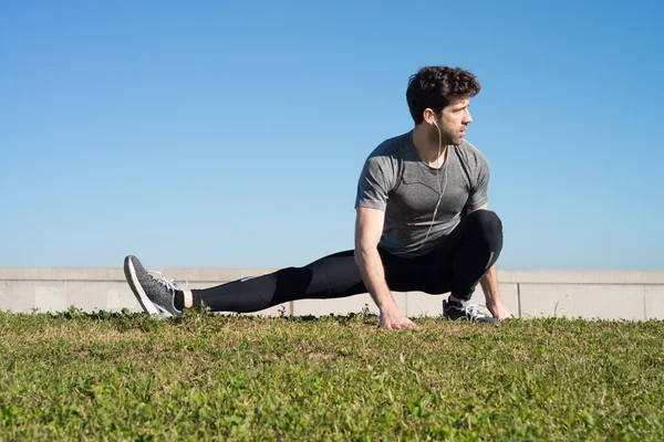 Man stretches leg in the ground in the grass — Stock Photo, Image