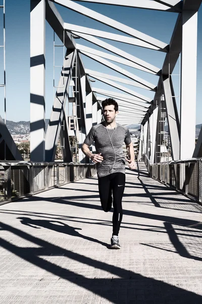 Young man running by metal bridge — Stock Photo, Image