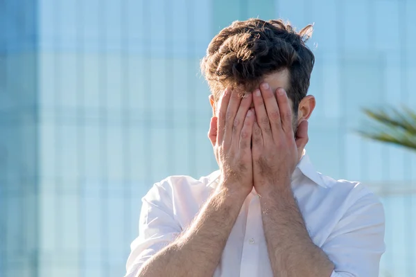 genç adam yüzünü elleri ile kaplı.