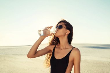 Çölde siyah mayolu güzel bir kız. Güneş gözlüklü genç kız.