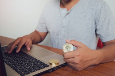 İşadamı dizüstü bilgisayarında altın bir Bitcoin tutuyor. Bitcoin ile para kazanmak, dijital para birimi para yatırım konsepti, engelleme zinciri transferi.