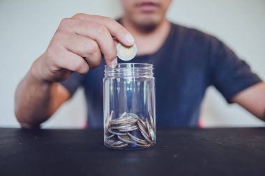 Elinde bozuk para tutan adam bardağa koyuyor, muhasebe konsepti için para biriktiriyor..