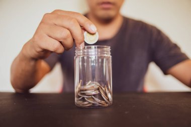 Elinde bozuk para tutan adam bardağa koyuyor, muhasebe konsepti için para biriktiriyor..