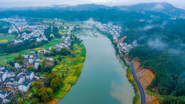 İlkbaharda, Çin 'in Jiangxi Eyaleti' nin Wuyuan kentinin kırsal arazisi teraslı yamaçların tepesinde çiçek açan kolza çiçeği manzarası..