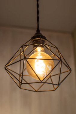 Metal çerçeveli sıra dışı bir avize. Işıklar açık.