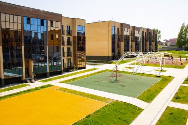 Çok katlı tuğla binalar ve çocuk parkı kompleksi. Şehir manzarası. Boş zamanlarında avlusu olan alçak binalar..