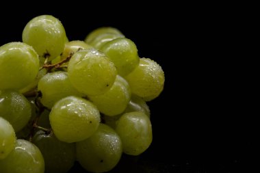 Siyah zemin üzerinde beyaz üzümler ve su damlaları.