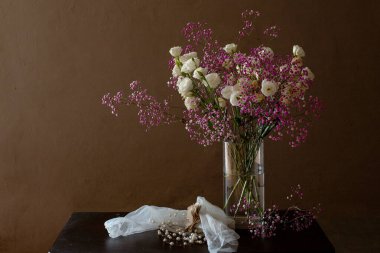 Boncuklarla dolu bir masada hayat dolu narin bir çiçek buketi