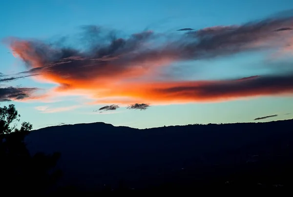 Beautiful red cloud illuminated by the last light of sun at dusk at the Andean mountains of central Colombia.