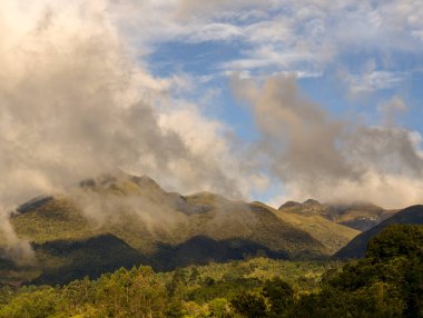 Kolombiya 'nın merkez And Dağları' nın panoramik manzarası gün batımının ışığıyla aydınlanıyor ve yoğun bulutlarla kaplanıyor..