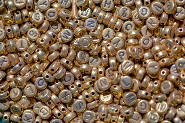 Macro photography of a heap of golden letter beads