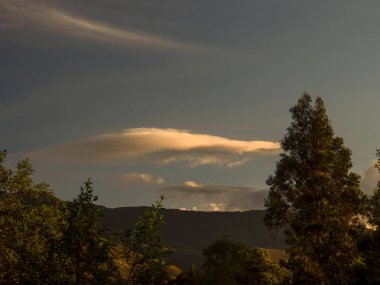 Kolombiya 'nın orta And Dağları günbatımında çoğunlukla açık bir gökyüzü ve sömürge şehri Villa de Leyva yakınlarındaki bazı ağaçlarla.