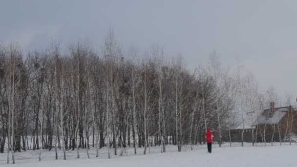 近くの森は正統派教会に男です。地面に降る雪のフレークを表示 — ストック動画