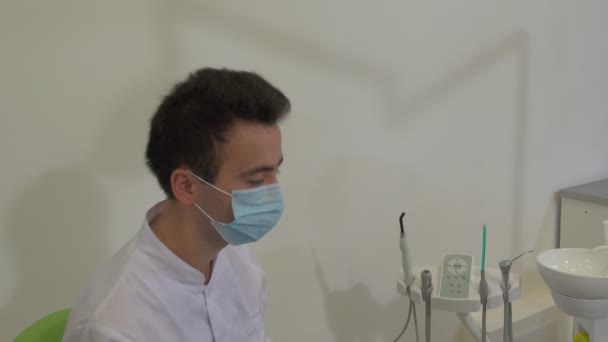 Dentist Takes a Lamp Down Starts to Examinine Client Girl Teeth of a Patient at Dental Treatment Room Young Man Doctor in Mask is Working With Tools — Stock Video