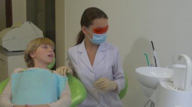 Gözlük Diş Hekimi Bir Diş Lambası Hasta Genç Blonde Kız Çocuk Sandalyede Oturuyor Doktor Maske Lab Coat Bir Kız Diş Kliniği konuşuyor