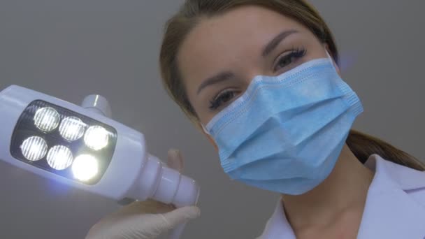 Vrouwelijke tandarts houdt een tandheelkundige haak staande op een patiënt arts is gekleed in Lab Coat masker handen in handschoenen onderzoeken van een tanden tandheelkundige kliniek — Stockvideo